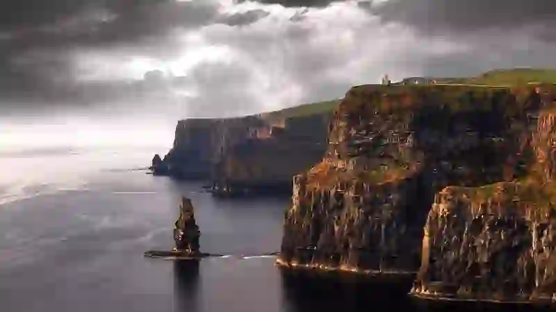 Moody Atlantic light over the Cliffs of Moher with a rugged sea stack and O’Brien’s Tower on the headland.
