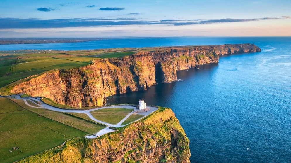 Aerial sunrise view of the Cliffs of Moher with O’Brien’s Tower perched above the Atlantic along the County Clare coastline.