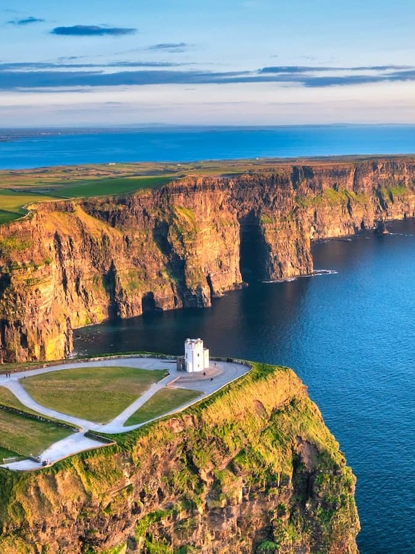 Aerial sunrise view of the Cliffs of Moher with O’Brien’s Tower perched above the Atlantic along the County Clare coastline.