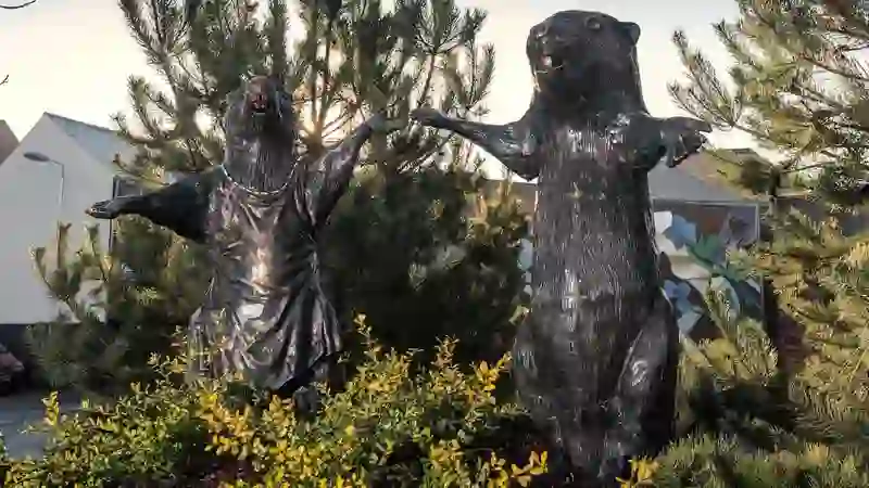 Bronze beaver statues holding hands in landscaped gardens at CS Lewis Square, Belfast.
