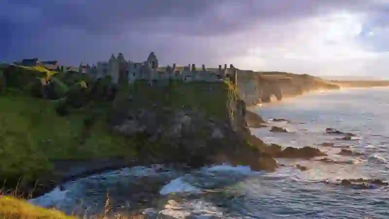 Dunluce Castle ruins perched on dramatic cliffs along the Causeway Coast at sunset.