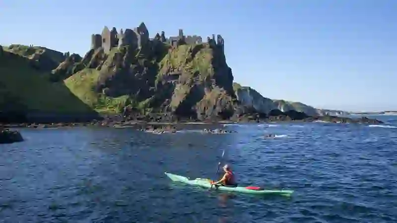 Kayaker paddling below Dunluce Castle on the Causeway Coast.