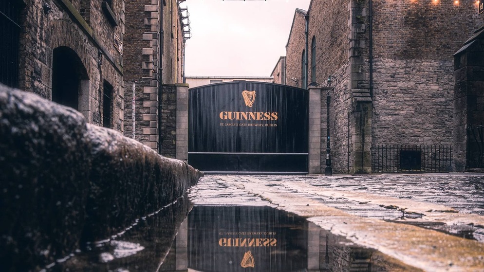 Guinness Storehouse gates at St James’s Gate Brewery in Dublin, with wet cobblestones after rain.