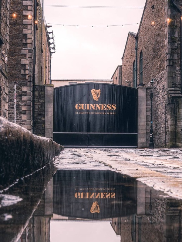 Guinness Storehouse gates at St James’s Gate Brewery in Dublin, with wet cobblestones after rain.