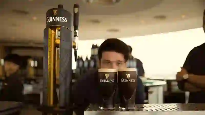 Bartender at the Guinness Storehouse in Dublin serving freshly poured pints of Guinness on tap at the Gravity Bar.
