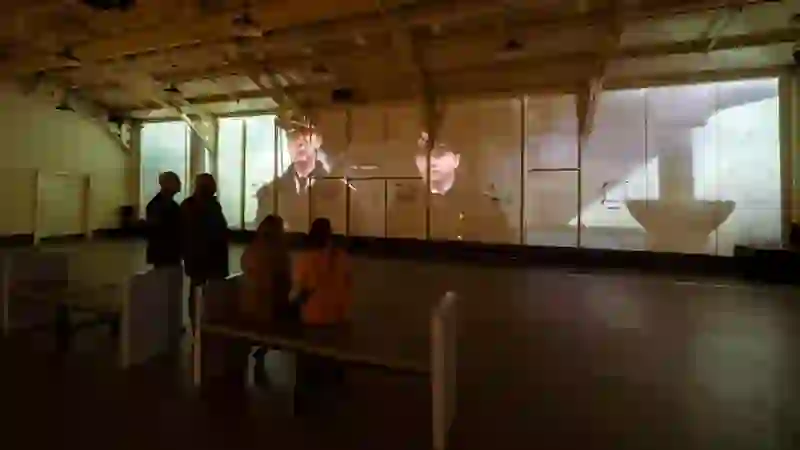 Visitors watching a projected film inside the Drill Hall of HMS Caroline in Belfast.