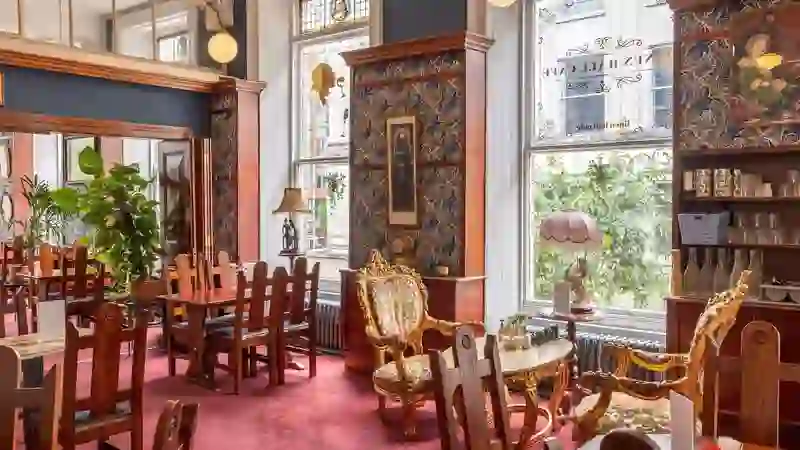 Victorian-style café interior at the Linen Hall Library, Belfast, with ornate chairs and large windows.