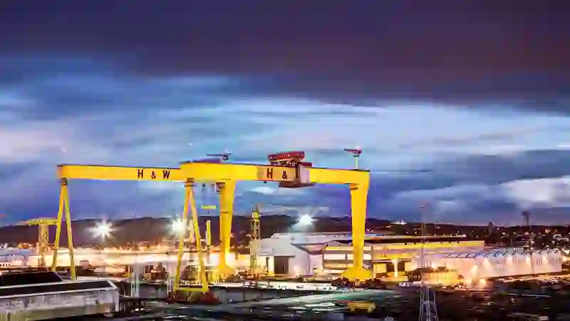 Harland & Wolff’s iconic yellow shipyard cranes lit up against a deep evening sky in Belfast.