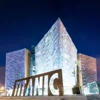 Titanic Belfast illuminated at night, with its angular silver façade and iconic Titanic sign in Belfast, County Antrim.