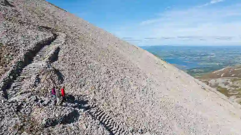 Hikers descend the rocky path on Croagh Patrick with sweeping views across Clew Bay.