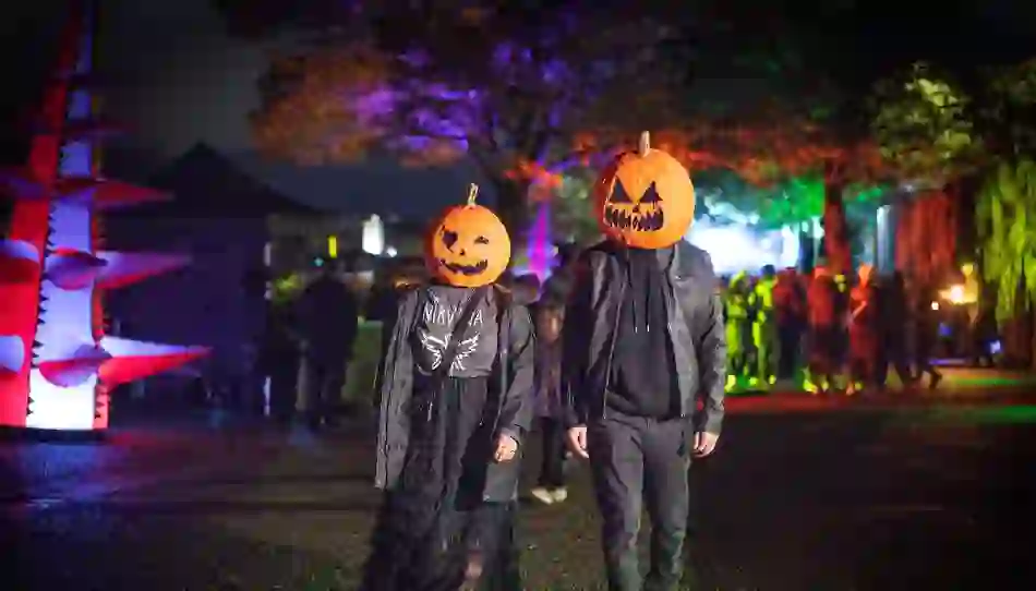 Two people with carved pumpkin masks walk through a Halloween festival in Derry~Londonderry.