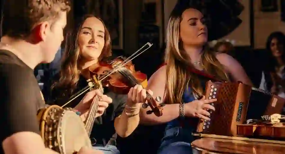 Traditional Irish music session with fiddle, banjo and accordion players performing in a cosy Belfast pub.