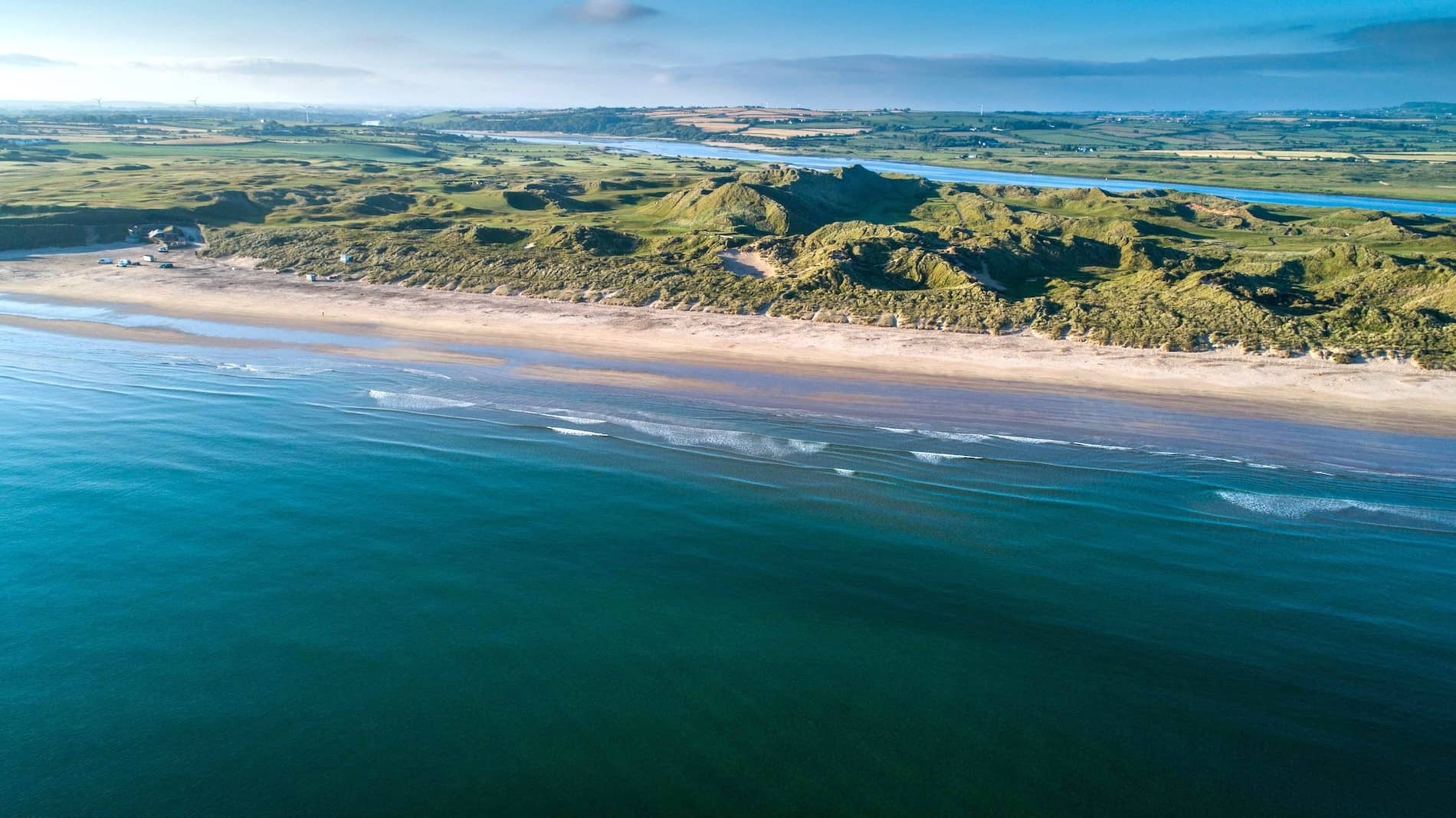 Aerial view of Portstewart Golf Club's links course beside a long sandy beach in County Londonderry.
