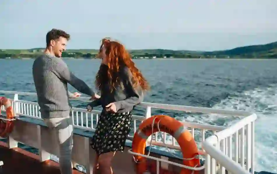 A man and woman smile in the sea breeze on the ferry, crossing between Ballycastle and Rathlin Island.