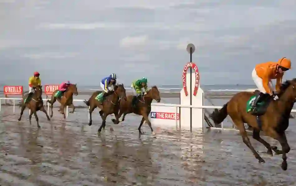 Jockeys on galloping horses race across the wet sands at Laytown Beach, County Meath.