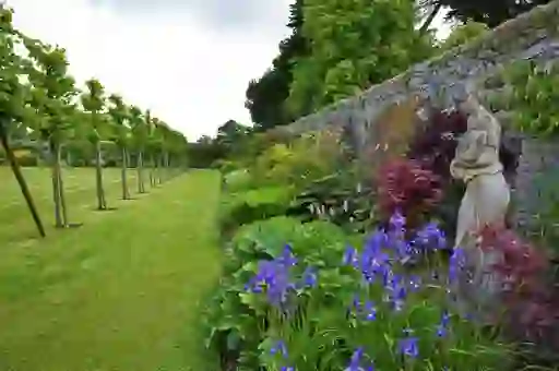 Stone statue among colourful flowers in Glenarm Castle garden, Antrim.