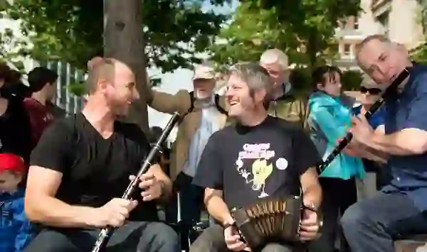 Traditional musicians performing outdoors at Fleadh Cheoil in Ennis, Clare, surrounded by smiling festival-goers.