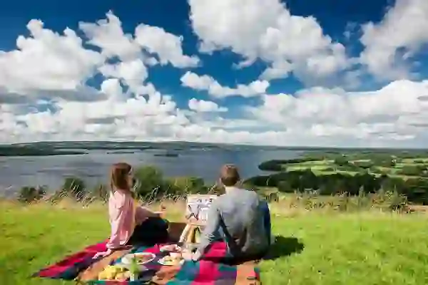Couple enjoying a picnic on a hillside blanket overlooking Lough Derg from The Lookout in Portroe, County Tipperary.
