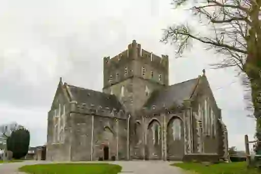 St Brigid’s Cathedral in Kildare, a medieval stone church with a central tower and arched windows.