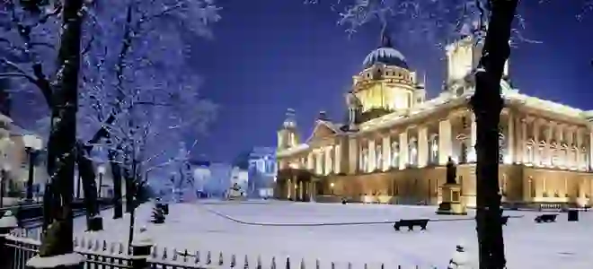 Snow-covered Belfast City Hall illuminated on a winter's night in Northern Ireland.